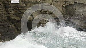 Powerful waves hitting rocky cliffs and falling to produce froth and splashes