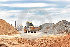 Powerful wheel loader or bulldozer at the construction site. Loader transports sand in a storage bucket. Powerful modern equipment