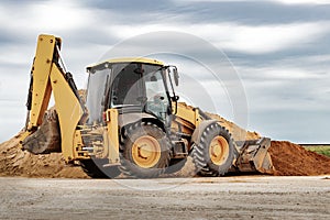 Powerful wheel loader or bulldozer at the construction site. Loader transports sand in a storage bucket. Powerful modern equipment