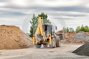 Powerful wheel loader or bulldozer at the construction site. Loader transports sand in a storage bucket. Powerful modern equipment