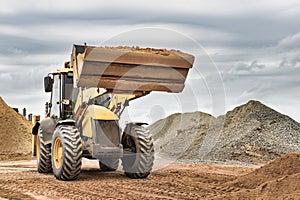 Powerful wheel loader or bulldozer at the construction site. Loader transports sand in a storage bucket. Powerful modern equipment