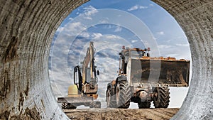 Powerful wheel loader or bulldozer working and mini excavator against blue cloudy sky. Modern equipment for earthworks. Rental of