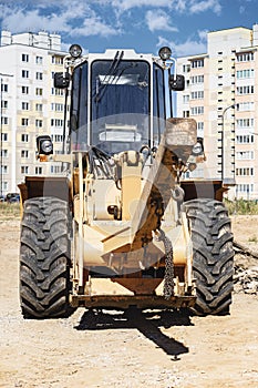 Powerful wheel loader for transporting bulky goods at the construction site of a modern residential area. Construction equipment