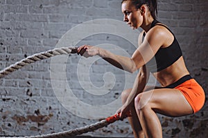 Powerful woman do workout with battle ropes in gym