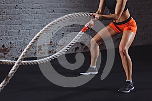 Powerful woman do workout with battle ropes in gym