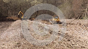 Powerful yellow earthmover crumbles sand at erection site. Bulldozer paving road. Crawler excavator.