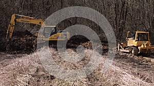 Powerful yellow earthmover crumbles sand at erection site. Bulldozer paving road. Crawler excavator