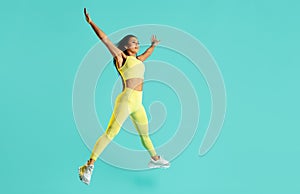 Powerful young brunette woman jumping over blue background. Power and motivation concept.