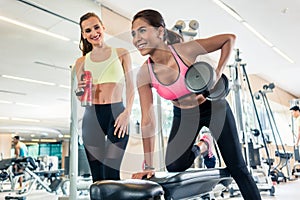 Powerful young woman smiling while rowing with one arm in a tren