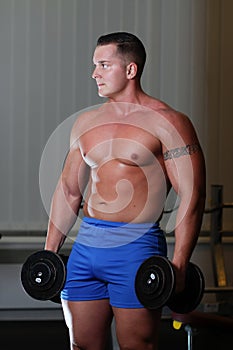 Powerlifter with dumbels in gym