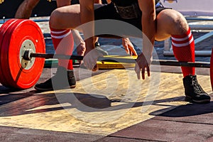 Powerlifter preparing for deadlift of barbell during competition of powerlifting