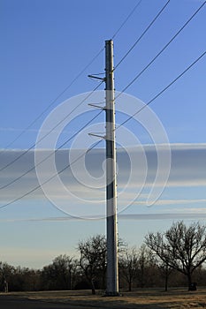 A Powerline metal pole with cables and blue sky with clouds and trees