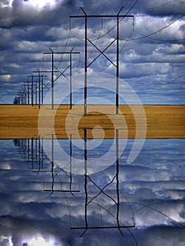 Powerlines in Field with Blue Sky and Clouds Reflection in Water photo