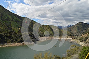 Powerlines over Reservoir in San Gabriel Mountain Sloping Top with Great White Clouds