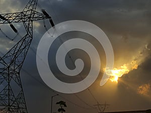 Powerlines with a Red sun setting behind a dark cloud