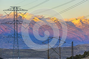 Powerlines silhouetted agains a mountain at sunet