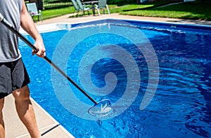 Poy using a skimmer to collect leaves out of a swimming pool