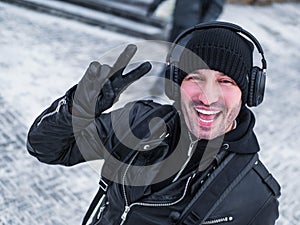 Pozitive man in headphones walkink in the street in winter time