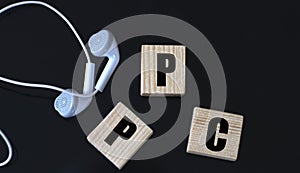 PPC - acronym on wooden cubes on a black background with headphones