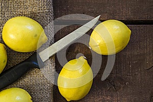PPhotos of lemon with knife on wooden floors, hand-cut half a lemon, dividing a lemon into two equal parts, cutting fresh lemon wi photo