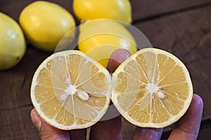 PPhotos of lemon with knife on wooden floors, hand-cut half a lemon, dividing a lemon into two equal parts, cutting fresh lemon wi photo