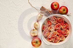 Ðpple pie in the baking dish decorated with fresh sliced apples and cinnamon sticks. Vegetarian tart on the white background