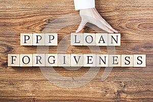 PPP LOAN Forgiveness text on wooden background, hand with percentage sign