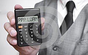 PPP LOAN word text inscription on calculator in a male hand of a businessman in white shirt and blue tie, Concept of finance and