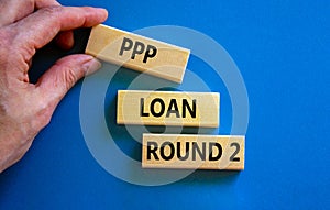 PPP, paycheck protection program loan round 2 symbol. Concept words PPP loan round 2 on blocks on blue background. Businessman