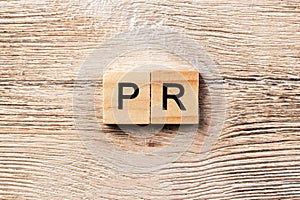 Pr word written on wood block. public relation text on table, concept