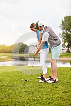 Practice makes perfect. an affectionate young couple spending a day on the golf course.