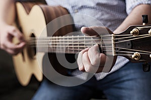 Practice makes perfect. Cropped shot of an unrecognizable man playing an acoustic guitar at home.