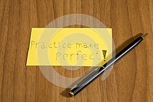 Practice makes perfect handwrite on a yellow paper with a pen on