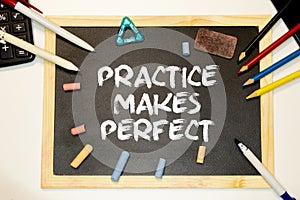 Practice Makes Perfect lettering in white chalk on a black board