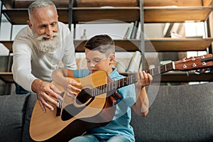 Loving grandfather and grandson having guitar practice