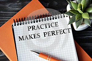 PRACTICE MAKES PERFECT - words in white notebook on dark wooden background with cactus and pen