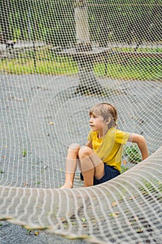 practice nets playground. boy plays in the playground shielded with a protective safety net. concept of children on line