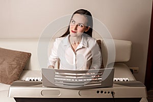 Practice playing the synthesizer, frontal portrait of a woman on an electronic piano