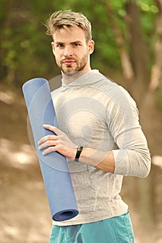 Practice yoga in park. Athlete always stretching after workout. Sportsman carries fitness mat for outdoor training