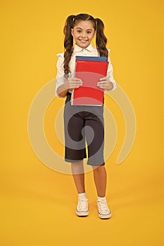 Practise your reading skills. Cute small child holding reading books on yellow background. Adorable little schoolgirl
