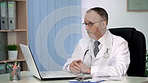 Practitioner carefully reading medicine article on laptop, self-education