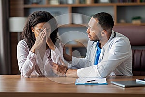 Practitioner consoling crying woman patient, clinic interior