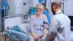 Practitioner measures senior retired woman blood pressure