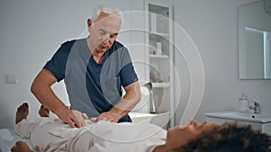 Practitioner touching woman stomach in hospital ward. Doctor massaging patient