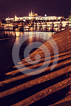 Prague castle and Charles bridge mirroring in Vltava river, nigh