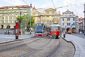 Old and modern trams on main square of Prague`s Mala Strana next to St. Nicholas Church