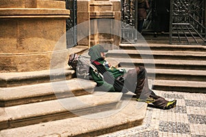 Prague, Czech Republic December 24, 2016 - Homeless hungry poor man sitting on the sidewalk in the city center. Unhappy