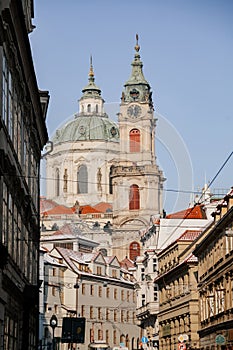 Prague, Czech Republic, 15 December 2022: View of Baroque Church of Saint Nicholas, green dome and bell tower with clock, sunny