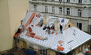 Prague, Czech Republic. Red roofs of Prague. Workers on top of the roof repairing slates