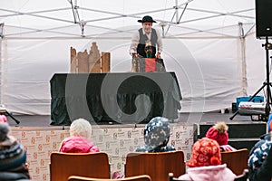 Prague, December 18, 2016: Design market in Prague - man in hat and suit shows puppet theater on street stage in front